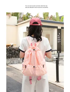 Lifestyle view of a pink nylon drawstring backpack being worn by a model in an outdoor setting.
