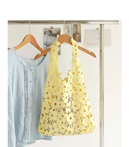 Detail view of yellow floral crochet shoulder bag hanging on a wooden clothes rack