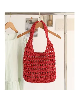 Close-up detail of a red handmade woven crochet shoulder bag with a hollow-out pattern