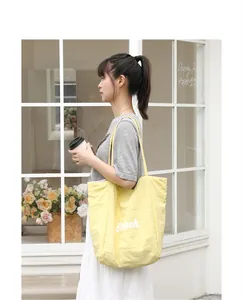 Bolso tote de nailon amarillo con estampado 'Beach' llevado en un entorno casual de estilo.