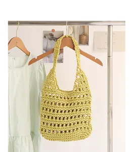 Hand-woven yellow cotton shoulder bag with hollow crochet design hanging on a rack.