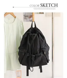 Detail view of a black pleated nylon drawstring backpack hanging on a clothing rack