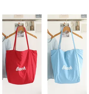Detalle de los bolsos tote de nailon rojo y azul claro con estampado de letras Beach