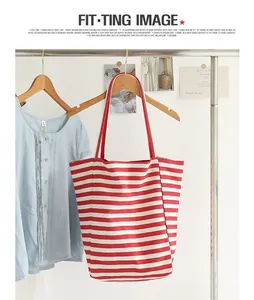 Detail view of a stylish red and white striped canvas tote bag hanging on a rack