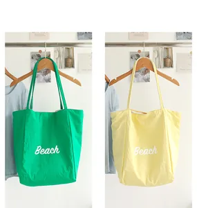 Vista detallada de bolsos tote informales de nailon verde y amarillo con estampado Beach