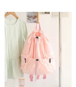 Fashionable pink drawstring nylon backpack with pleated design hanging in a closet