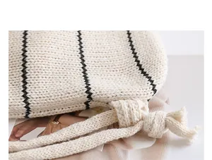 Detailaufnahme einer cremefarbenen Stricktasche mit schwarzen Streifen und Kordelzug