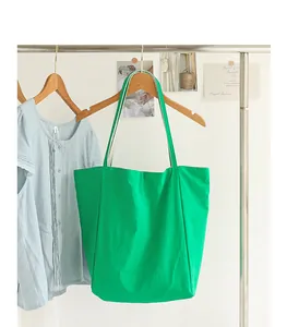 Primer plano de un bolso tote de nailon verde vibrante colgado en una percha de madera.