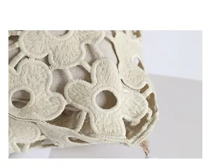 Detail shot of heavy floral embroidery and hollow-out texture on a cream lace bag.