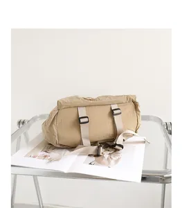Detail view of khaki grid nylon backpack with adjustable straps on a minimalist tray.