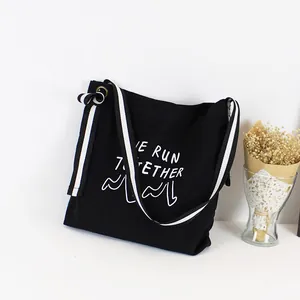 Primer plano de bolso de lona negro con estampado 'WE RUN TOGETHER' y correa.