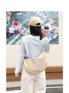 Bolso dumpling beige de cuero PU suave mostrado por una modelo en un entorno urbano.