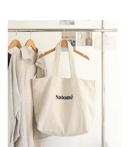 Detailed view of the minimalist Salomé linen tote bag hanging on a wooden hanger in a studio.