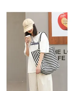 Close-up of a stylish striped canvas tote bag worn by a model in casual setting