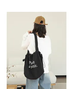 Mujer con un bolso tote de lona negro con cordón y estampado Petit a petit blanco