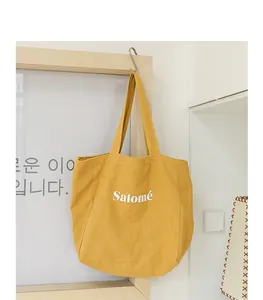 Detail view of the yellow linen tote bag with Salomé text hanging on a wooden frame