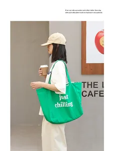 Detailed view of casual green nylon tote bag with white lettering carried by a model