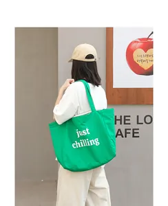 Green nylon tote bag with white 'just chilling' print shown in lifestyle setting