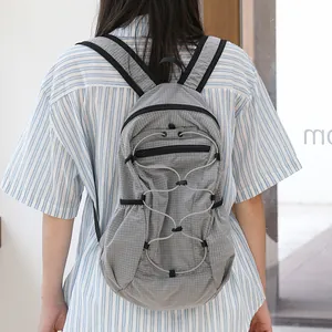 Minimalist grey grid nylon backpack with drawstring detail shown on model back.