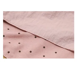 Macro detail of pink nylon tote bag showing polka dot pattern and fine stitching