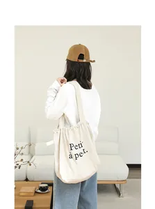 Mujer con un bolso de algodón y lino beige con cordón y el texto 'Petit à petit'