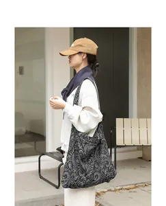 Vue latérale détaillée d'un sac bandoulière en toile noire avec broderie vintage