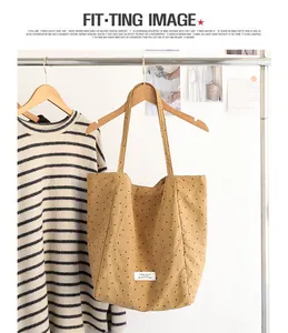 Detail of a Japanese style khaki polka dot canvas tote bag hanging on a wooden hanger