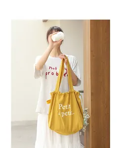 Detalle de estilo de vida del bolso de lona amarillo con cordón y estampado Petit