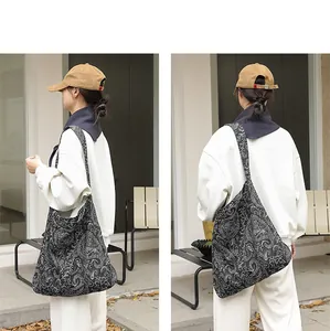 Vue détaillée d'un sac bandoulière en toile noire avec des motifs de broderie paisley complexes