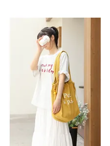 Primer plano detallado del bolso tote de lino amarillo con cordón y letras blancas