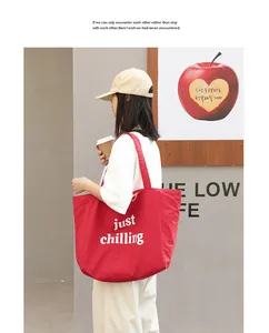 Casual red nylon tote bag with white just chilling print worn by a woman outdoors.