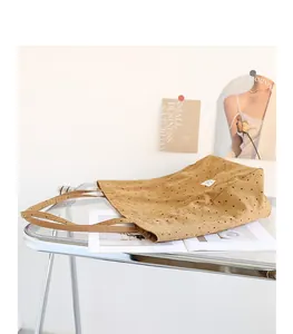 Close-up of a brown polka dot canvas tote bag placed on a transparent glass desk