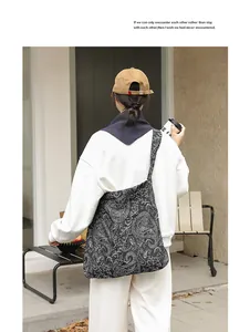 Vue détaillée d'un sac bandoulière vintage en toile noire à motif paisley sur un mannequin.