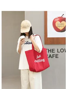 A vibrant red nylon tote bag featuring 'just chilling' print, carried by a model in casual outfit.