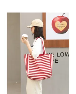 Close-up detail of a casual red and white striped canvas tote bag styled on a model