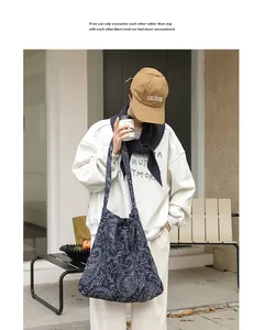 Détail d'un sac à bandoulière rétro en toile brodée bleu marine porté par un mannequin