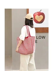 Detailed view of a casual red and white striped tote bag carried on a woman's shoulder