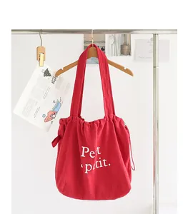 Elegante bolso de algodón y lino rojo con cordón e impresión de letras blancas en percha