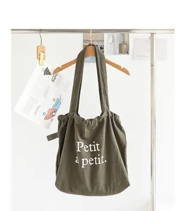 Vista detallada del bolso tote de lino verde oliva con cordón e inscripción Petit à petit