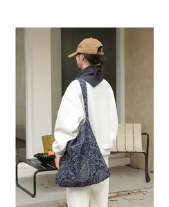 Vue détaillée d'un sac hobo en toile cachemire bleu marine porté par un mannequin en extérieur