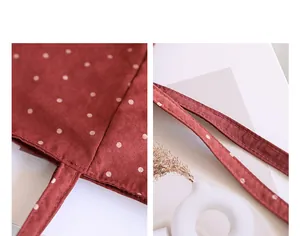 Macro detail of red polka dot canvas tote bag focusing on durable stitching and straps