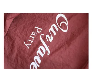 Detailed close-up showing white cursive letter print on red crinkled nylon fabric tote bag