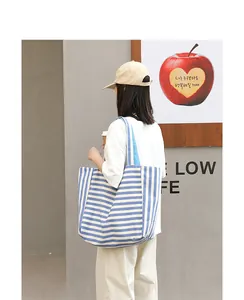 Casual blue and white striped canvas tote bag shown as being carried by a model on the shoulder