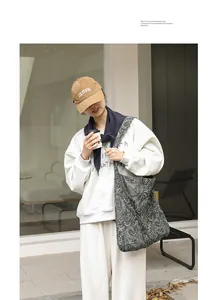 Vue détaillée d'un sac à bandoulière en toile à motif cachemire porté par un mannequin.