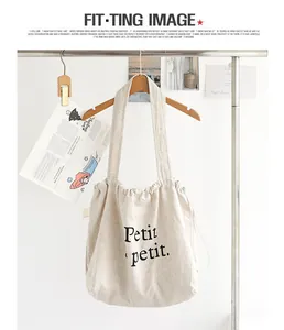 Detalle de un bolso tote de algodón y lino beige con estampado de texto Petit petit