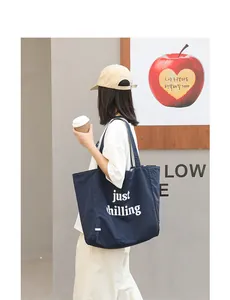 Model wearing a navy blue nylon tote bag with 'just chilling' print in a street setting.