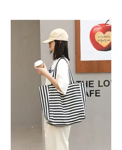 Lifestyle shot of a striped canvas tote bag carried by a model in a casual setting.