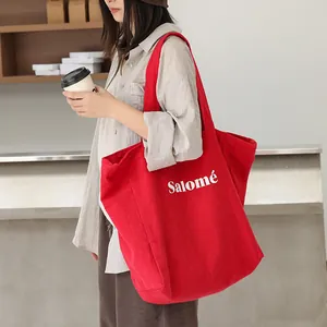 Large red linen tote bag with Salomé print carried by a model in a minimalist cafe setting