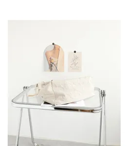 Primer plano de un bolso tote de lino plisado color crema en una mesa minimalista
