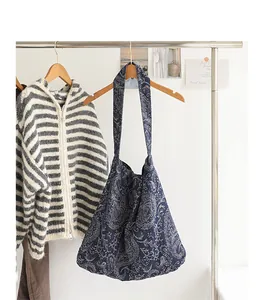 Vue détaillée d'un sac à bandoulière en toile bleue avec broderie paisley sur un support